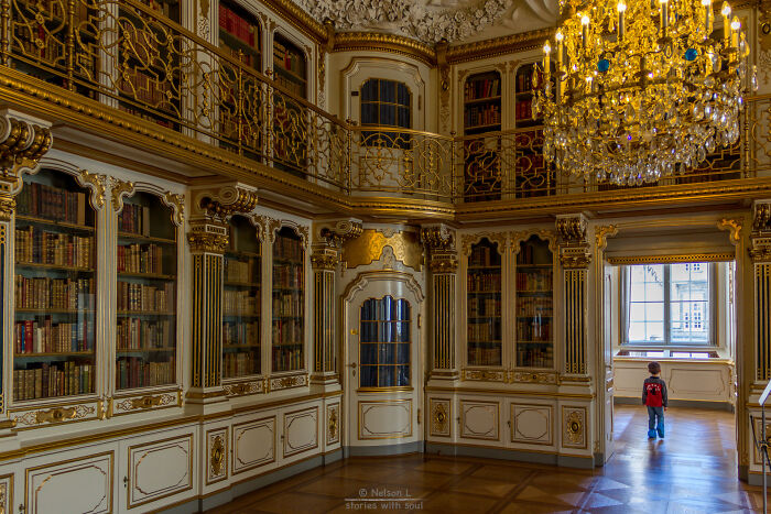 Grandiose library interior with ornate gold details, tall bookshelves, and a child exploring a magical bookstore setting.