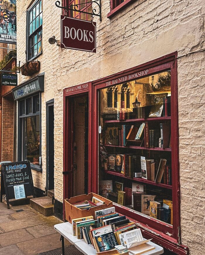 Librería acogedora y grandiosa con libros exhibidos en el exterior, con una fachada encantadora y un ambiente cálido y acogedor.