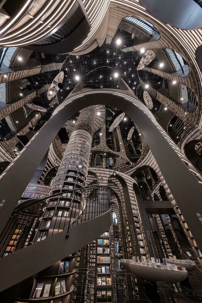 Grandiose library interior with towering bookshelves, spiral staircases, and reflective ceilings creating a magical atmosphere. Grandiose library interior with towering bookshelves, spiral staircases, and reflective ceilings creating a magical atmosphere.
