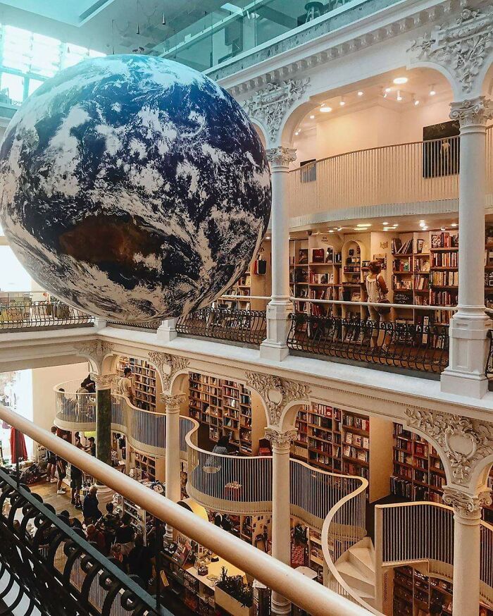 Grandiose library interior with ornate pillars, curved staircases, and a large Earth globe suspended above the bookshelves. Grandiose library interior with ornate pillars, curved staircases, and a large Earth globe suspended above the bookshelves.