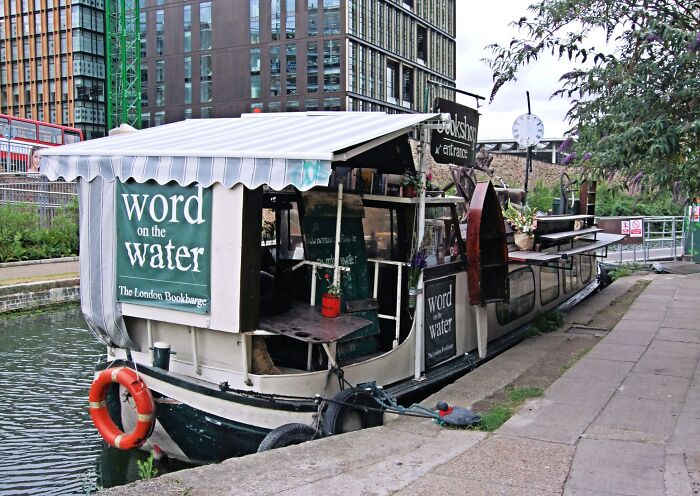Floating bookstore moored along a canal, showcasing a cozy and magical library experience on the water. Floating bookstore moored along a canal, showcasing a cozy and magical library experience on the water.