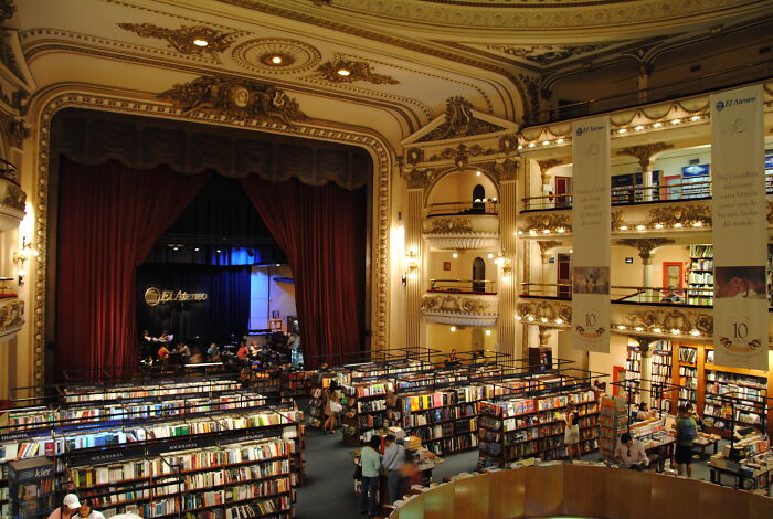 Grandiose library interior with ornate balconies and bookshelves filled with numerous books and visitors browsing. Grandiose library interior with ornate balconies and bookshelves filled with numerous books and visitors browsing.